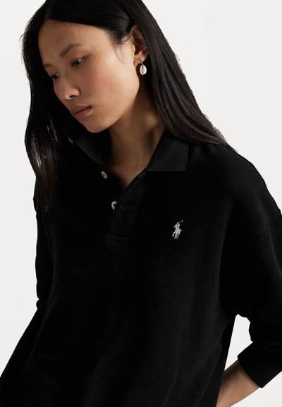 Schwarzes Poloshirt aus Baumwolle mit klassischem Kragen, Drei-Knopf-Leiste und einem kleinen weißen gestickten Logo auf der Brust.