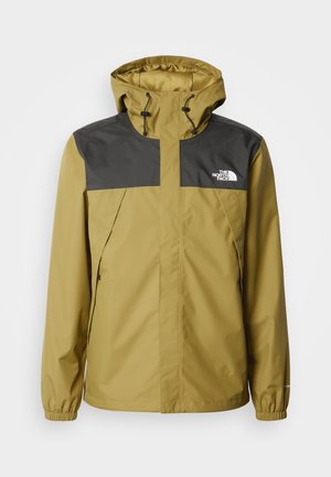 Žuta i siva vodootporna jakna s kapuljačom, elastičnim manšetama i logotipom na lijevoj strani prsa. Ima dva bočna džepa sa patentnim zatvaračima.