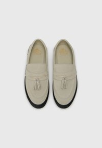 Light gray loafers made of suede, featuring a decorative tassel, black rubber sole, and stitched detailing.