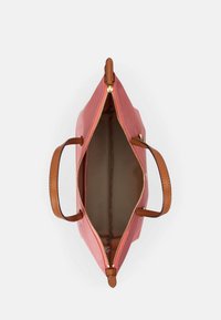 Różowa syntetyczna torebka z brązowymi skórzanymi uchwytami i złotym zamkiem. Wnętrze wykonane z beżowej tkaniny z przestronną komorą.