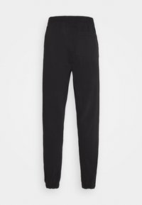 Pantalons de jogging noirs avec une taille élastique et des chevilles resserrées. Comprend une seule poche arrière et une texture de tissu lisse.