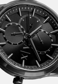 Schwarze Edelstahl-Uhr mit einem strukturierten schwarzen Zifferblatt, das silberfarbene Stundenmarker, Unterzifferblätter und drei Zeiger aufweist. Mit eingraviertem Logo akzentuiert.