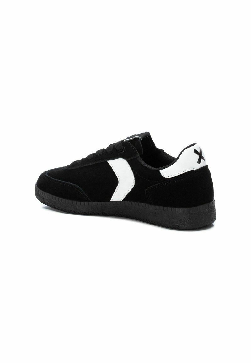 Sneaker in suede nero con un accento laterale bianco, suola piatta in gomma nera e tallone testurizzato. Presenta un design tradizionale con lacci e dettaglio del logo.