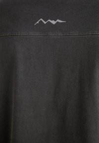 Black cotton t-shirt with a crew neck. Features a subtle grey mountain graphic on the upper back. Smooth texture with a relaxed fit.