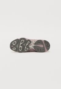 Chaussure de sport New Balance avec une tige violette, une semelle en caoutchouc et une semelle extérieure à motif avec des accents gris clair et des détails arrondis.