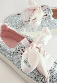 Baskets argentées scintillantes avec un dessus pailleté, des lacets en satin rose pâle, une doublure rose douce et une semelle en caoutchouc blanche.