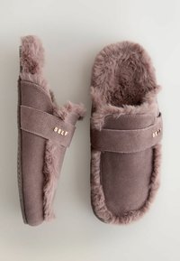 Rosa, mit Fell gefütterte Hausschuhe mit weichem Wildlederaußenmaterial, ausgestattet mit einem breiten Riemen, auf dem das Wort 'SELF' in Gold geprägt ist.