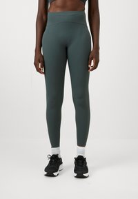 Magas derekú, sötétzöld leggings, rugalmas anyagból készült, sima textúrával és testhezálló kialakítással a kényelem és a szabad mozgás érdekében.