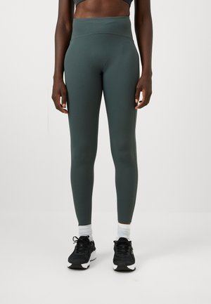 Leggings taille haute, de couleur vert foncé, fabriqués en tissu extensible, présentant une texture lisse et un design ajusté pour le confort et la liberté de mouvement.