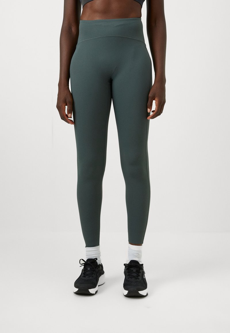 Magas derekú, sötétzöld leggings, rugalmas anyagból készült, sima textúrával és testhezálló kialakítással a kényelem és a szabad mozgás érdekében.