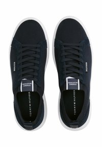 Marineblaue Sneaker mit einem strukturierten Mesh-Obermaterial, runder Zehenpartie, weißer Sohle und kontrastierendem Logo an den Seiten und auf der Zunge. Schnürdesign.