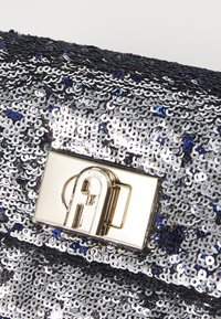 Sølvfarvet paillet clutch taske med en blank overflade, der har en klips i guldfarvet tone og blå detaljer. Flad, rektangulær design.