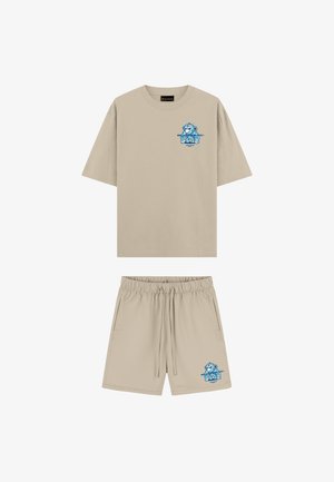 Beige T-shirt met korte mouwen en korte broek set met blauwe cartoon aap op de linkerborst en linkerbeen, elastische tailleband bij de korte broek.