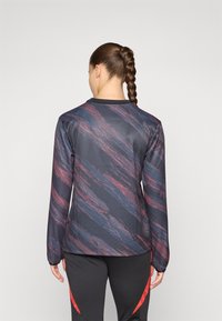 Langsleeve sporttop in zwart met een gestructureerd, donkerblauw en bordeaux abstract patroon. Heeft een ronde halslijn en een gladde afwerking.