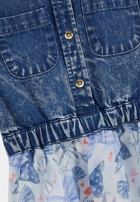 Sukienka dżinsowa z teksturowanym niebieskim topem z dwiema kieszeniami na piersi, złotymi guzikami oraz falbaniastej, przezroczystej spódnicy z wzorem i grafiką motyli.