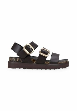 Sandalia negra con dos hebillas doradas ajustables, tiras anchas, plantilla de corcho y suela gruesa con relieve para uso casual.