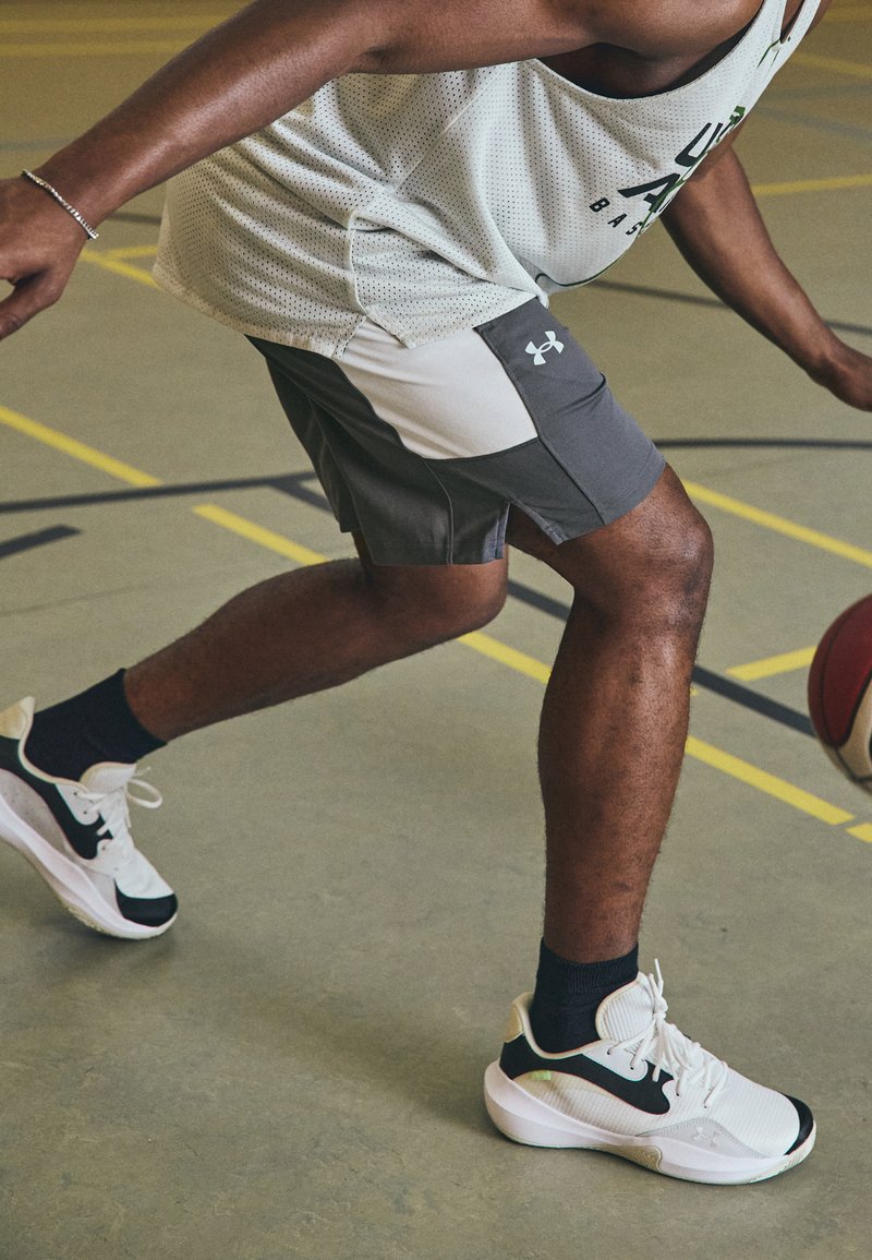 Bermudas deportivas en gris y blanco con un bolsillo lateral; material ligero. Zapatillas de baloncesto en negro y blanco con acentos verdes.