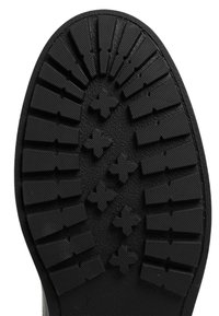 Semelle en caoutchouc noir présentant un design texturé avec des rainures et des motifs en croix pour l'adhérence, offrant durabilité et traction.