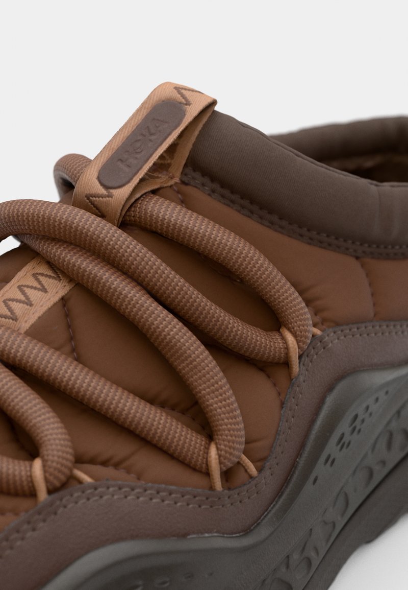 Bruine sneaker met een gewatteerd design. Heeft opvallende veters, een gestructureerde zool en een rubberen basis. Versterkte hiel met merklabel.