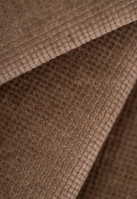 Brauner strukturierter Stoff mit einer weichen, flauschigen Oberfläche und einem karierten Muster, das eine gefaltete Erscheinung und subtile Tonvariationen aufweist.