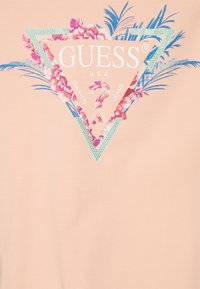 Lyserød bomulds T-shirt med et trekantet logo dekoreret med blomstermønstre, turkise accenter og trykt tekst. Glat tekstur, afslappet design.