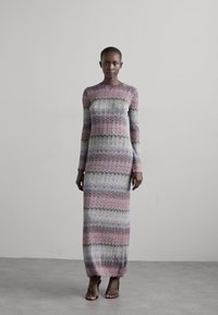 Rochie maxi dintr-un material tricotat texturat, în dungi pastelate de roz, verde și mov. Are mâneci lungi și un gât rotund.