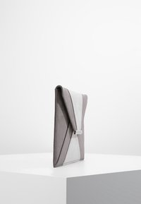 Grå mocka kuvertväska med en triangulär design. Har ett slätt lock och ett silverfärgade spänne, vilket skapar ett eleganta, minimalistisk utseende.