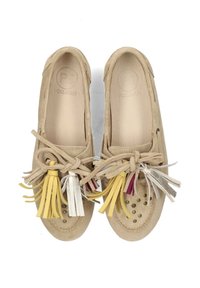 Mocassini beige in suede con nappine beige, gialle, bianche e borgogna legate sulla parte superiore, con borchie metalliche vicino alla punta arrotondata.