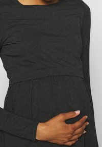 Mörkgrå amningsblus med långa ärmar, tillverkad av mjukt och elastiskt material, med en gathered midja och slät yta.