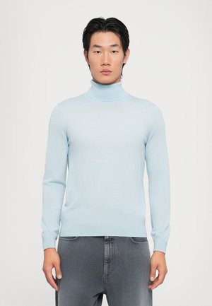 Suéter de cuello alto azul claro hecho de una tela suave, con mangas largas y un diseño ajustado, combinado con pantalones de mezclilla grises.