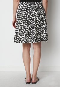 Jupe à motifs noir et blanc avec une silhouette loose, taille élastique et design mi-long. Tissu doux, style décontracté, sans poches visibles.