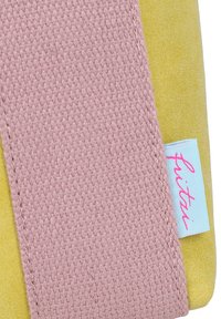 Tessuto giallo con una banda intrecciata rosa testurizzata. Presenta un'etichetta azzurra chiara con la scritta "fritai" in rosa. Forma piatta e rettangolare.