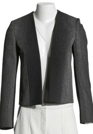 Blazer gris foncé texturé à ouverture frontale avec manches longues sur un torse de mannequin blanc portant un pantalon blanc.