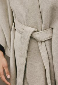 Helehallest mähis pehme tekstuuriga, sobiva sidumisrihmaga ja laiade varrukatega, edastades mugava ja juhusliku disaini.