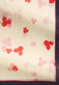 Transparante sjaal met een crèmekleurige achtergrond, voorzien van rode en roze bloemmotieven. Afgewerkt met een donkere rand en een delicate zoom.