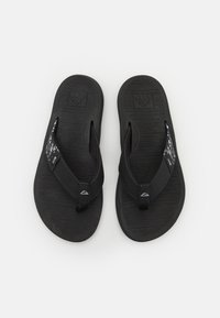 Tongs noires avec des semelles en caoutchouc texturé et des brides en tissu. Une bride présente un détail subtil de motif. Design léger et simple.