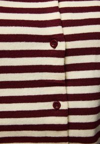 Bordo un krēmbaltas svītrains kardigans ar adītu tekstūru, priekšpusē apaļas bordo pogas aizdarei.