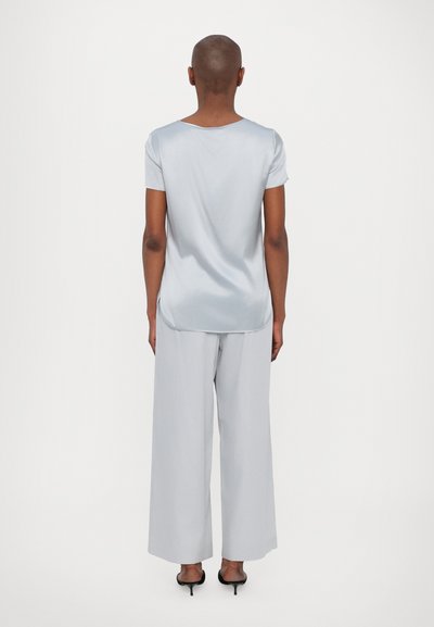 Blusa de manga curta azul clara com decote redondo, combinada com calças largas cinza claro. Tecido suave e ajuste descontraído.