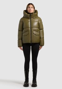 Olivgrüne Steppjacke mit großer Kapuze, Reißverschluss und zwei Fronttaschen. Hat eine glatte, glänzende Textur und einen lässigen, boxy Schnitt.