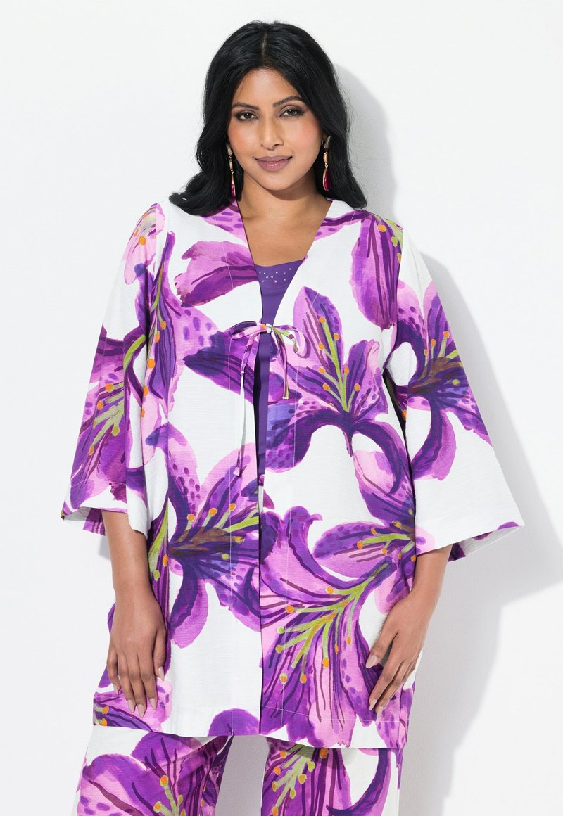 Blomster kimono-style top med lilla og hvide mønstre, udstyret med en båndlukning og brede ærmer, parret med en ensfarvet lilla top under.