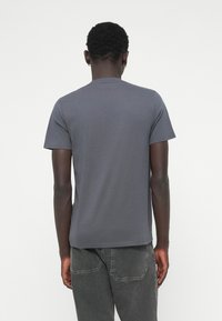 Tricou gri cu mâneci scurte, dintr-un material moale. Guler clasic rotund, croi lejer și design minimalist, fără logo-uri sau modele vizibile.