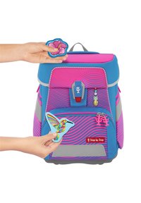 Blauwe en roze rugzak met een gestructureerde afwerking, voorzien van decoratieve patches, waaronder een roze bloem en een kleurrijk kolibrie-ontwerp.