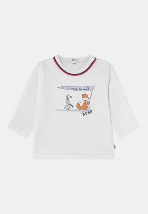 Hvid baby langærmet trøje med rød og blå kant omkring kraven, med en ræv og en kanin, der holder et flag med teksten "around the world" og "little BOSS".