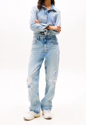 Light blue denim shirt with a patterned pocket, paired with distressed light blue jeans featuring frayed edges and patchwork details.