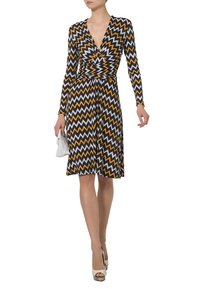 Vestido de manga larga con un patrón de espiga en negro, amarillo y blanco. Diseño cruzado con una cintura ajustada y falda acampanada.
