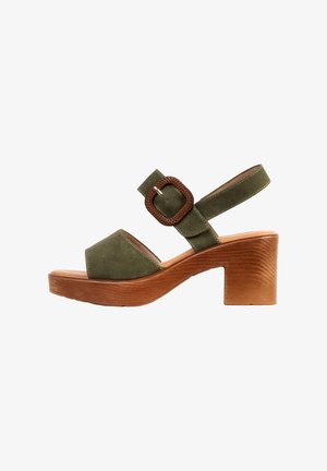 Sandale à bout ouvert en suède vert olive avec talon bloc en bois et bride ajustable ornée d'une grande boucle tissée.
