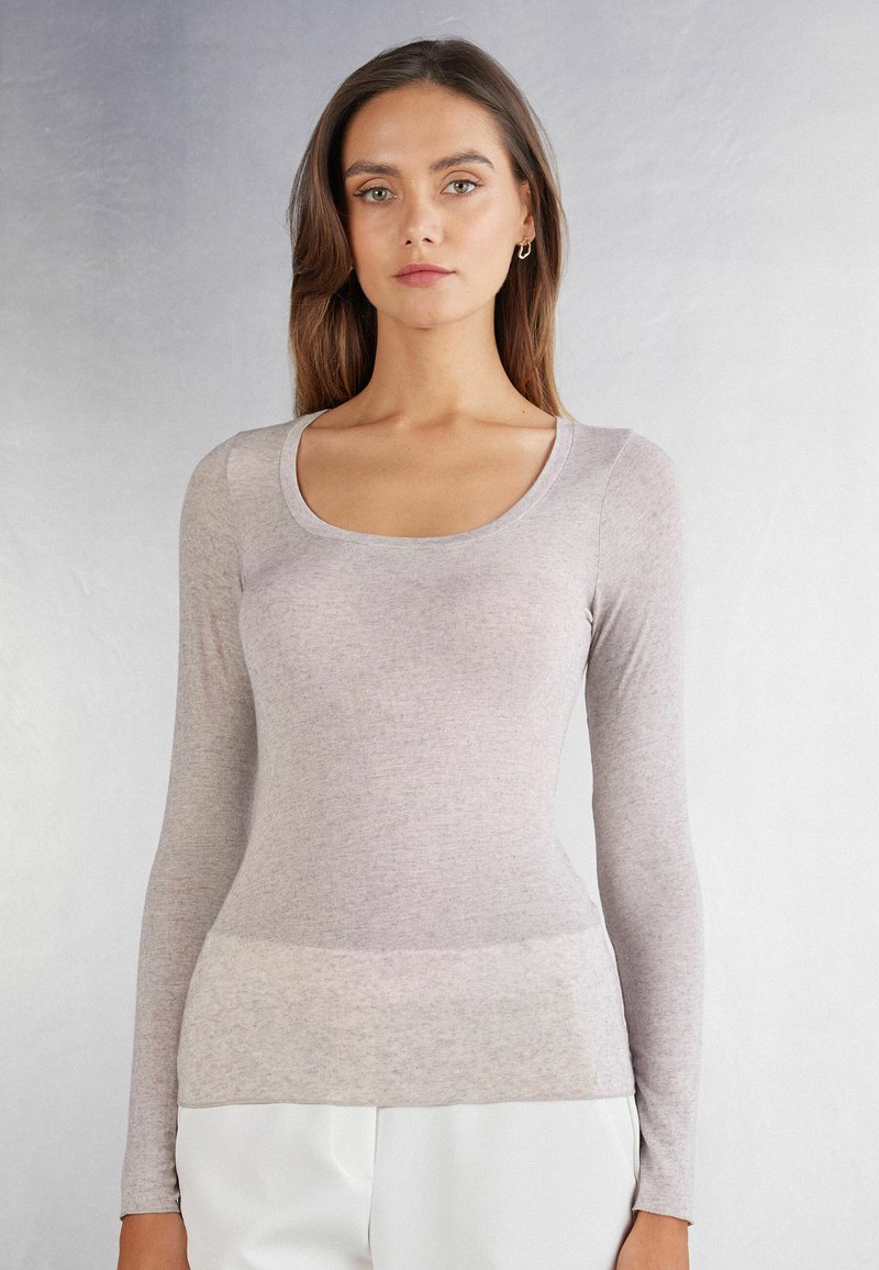 Hellgraues, langärmliges Oberteil aus weichem, strukturiertem Stoff mit einem runden Halsausschnitt und figurnahem Design, das an der Taille mit einem subtil helleren Band versehen ist.