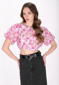 Blomster crop top i pink og hvid, transparent stof, puffede korte ærmer, elastisk kant. Kombineret med en højtaljet sort denimnederdel og bælte.