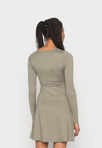 Vestido de mangas longas em tecido verde-azeitona. Corpete justo com saia ampla e decote redondo. Textura suave, design simples.
