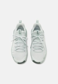 Lys grå trening sneakers med en teksturert mesh-overdel, flate snører, polstret tunga og en mørk såle. Minimalistisk design med subtil merkevare.